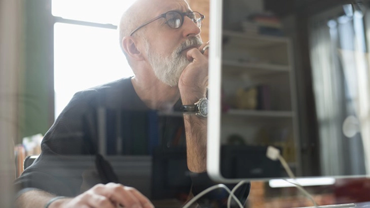 Man sitting at desk with hand on his chin