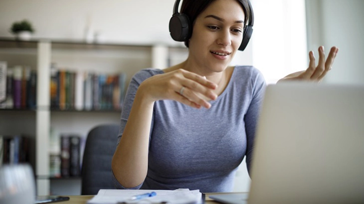 Woman wearing headphones and looking at laptop screen