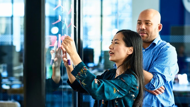 Man watching woman placing post-its on mirror