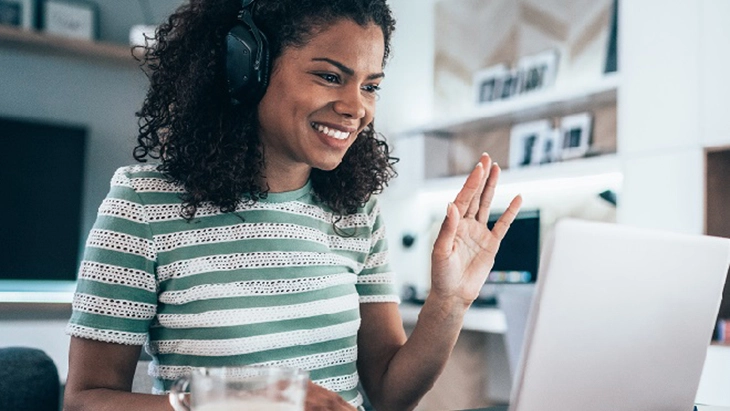 Woman smiling and using laptop and headphones