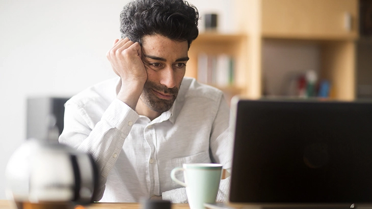 Man looking upset and looking at laptop