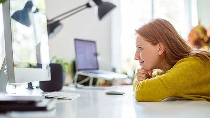 Woman leaning forward on desk and smiling