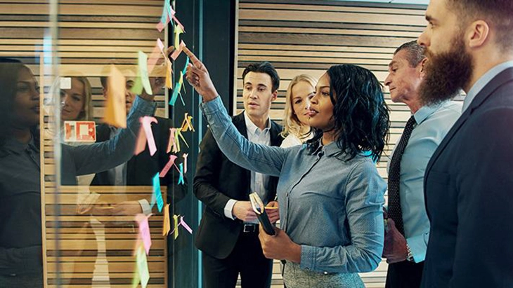 Colleagues sticking post it notes on a board