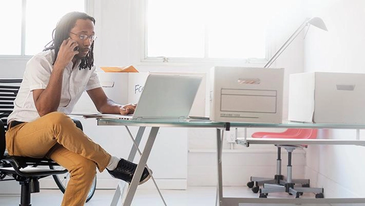 Man in office using laptop and mobile