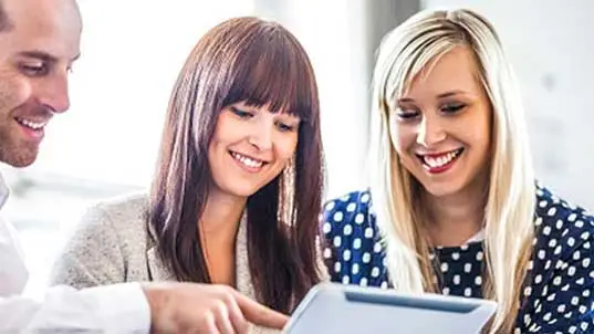 Two women and a man looking at laptop screen