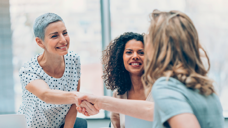 Women shaking hands and smiling in office