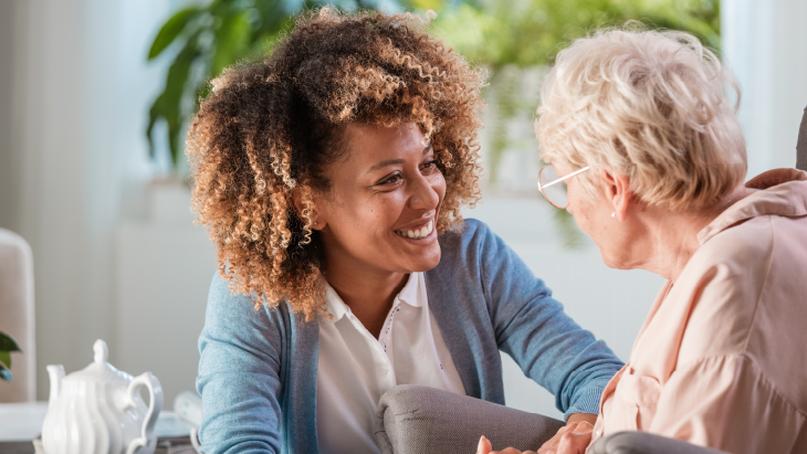 Young woman smiling and speaking with elderly woman