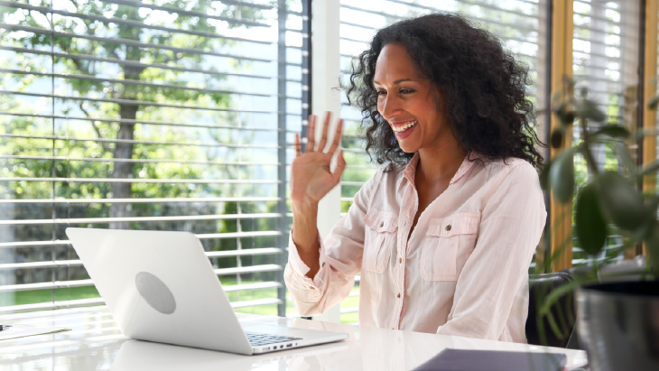 Woman in an online meeting and waving and smiling