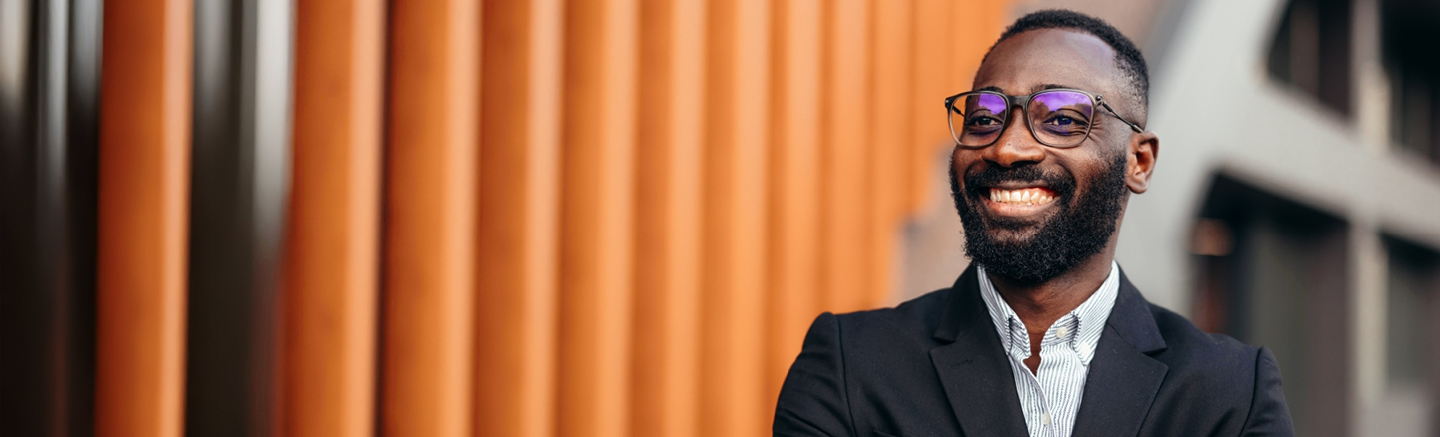 Professional in a suit standing confidently outside a modern building with orange vertical panels, representing Hays interview guide.